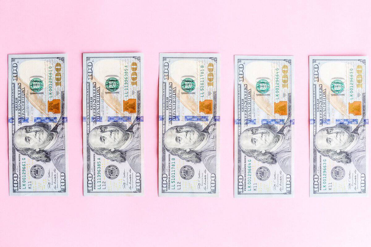 $100 bills laid out on pink background for financial or business concept.