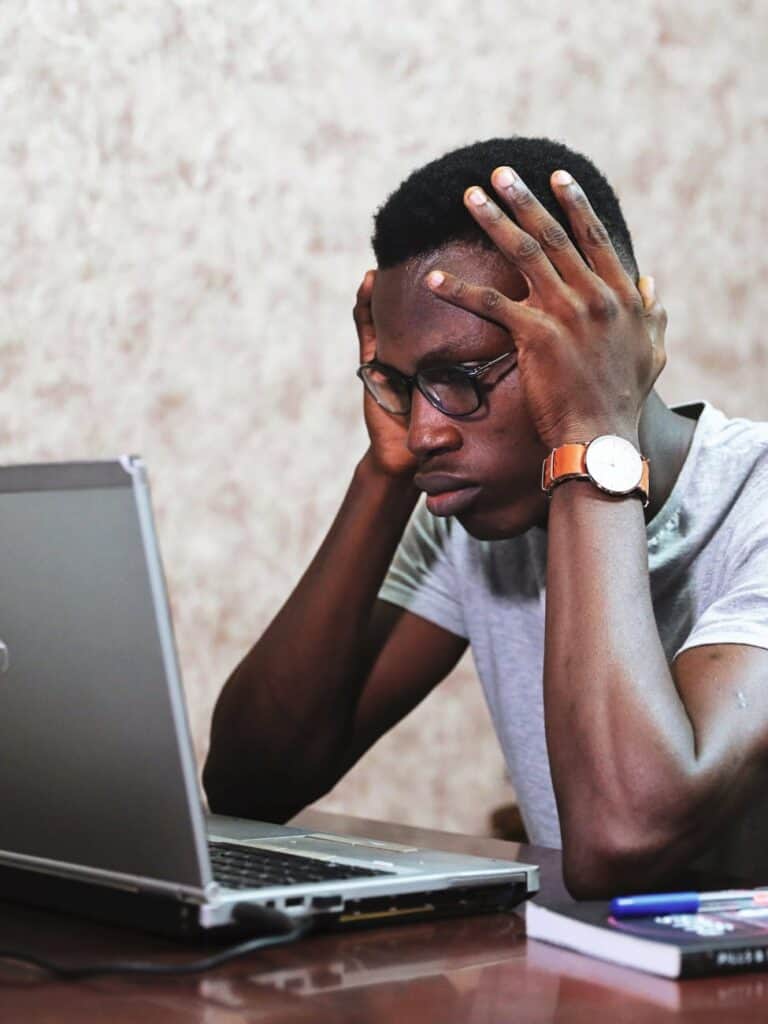 Stressed young man with glasses staring at laptop