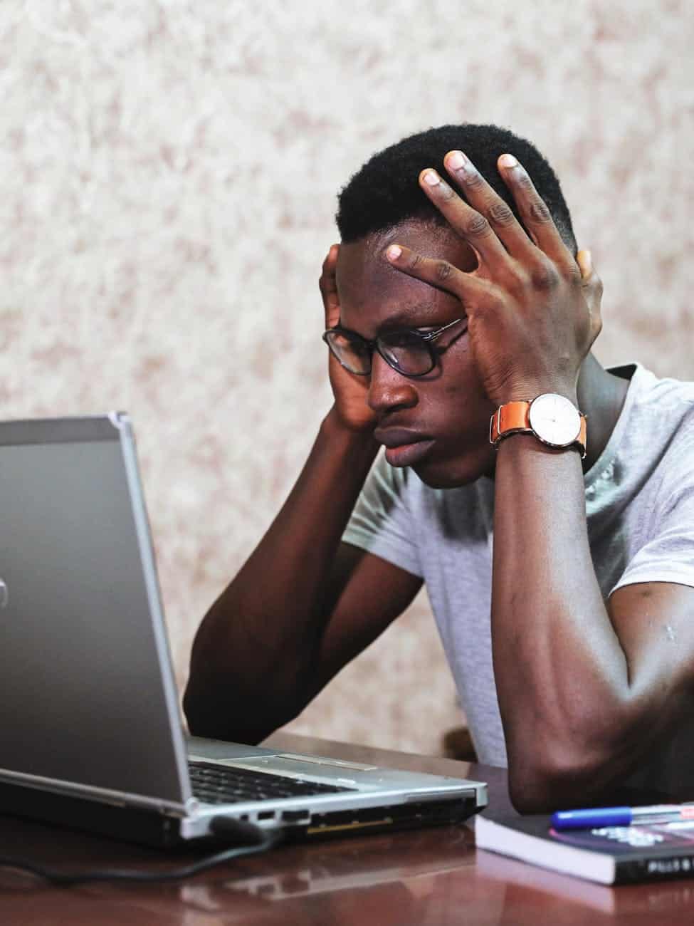 Stressed young man with glasses staring at laptop