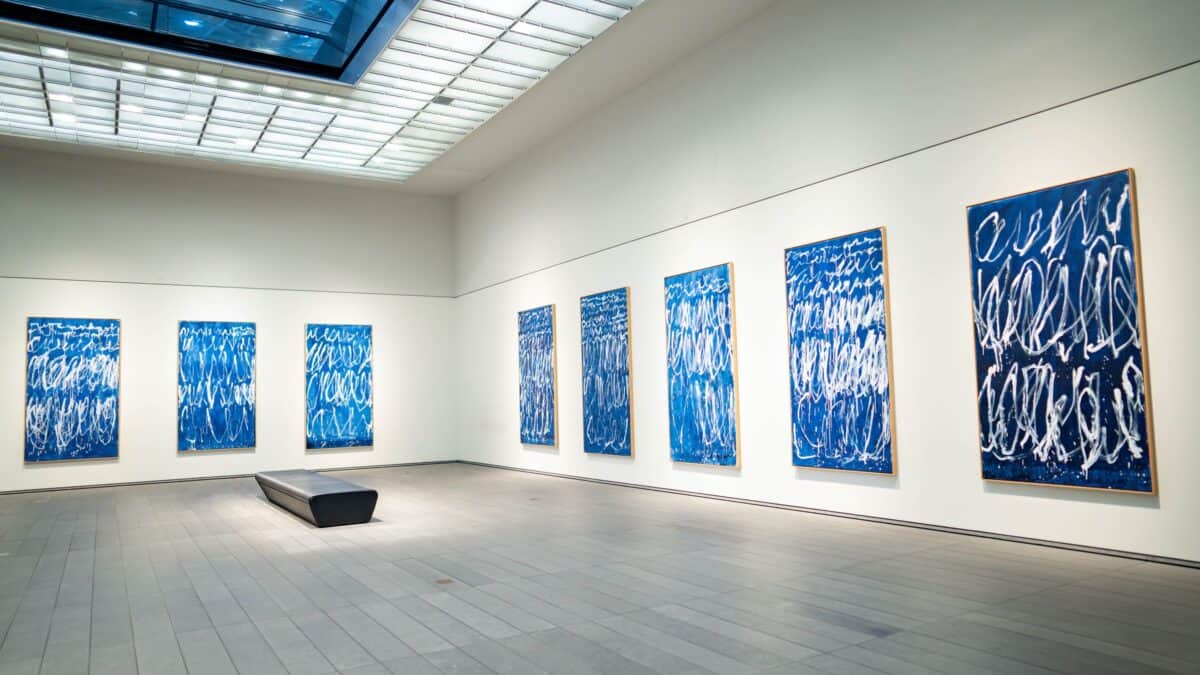 A spacious modern art gallery with abstract blue paintings on white walls
