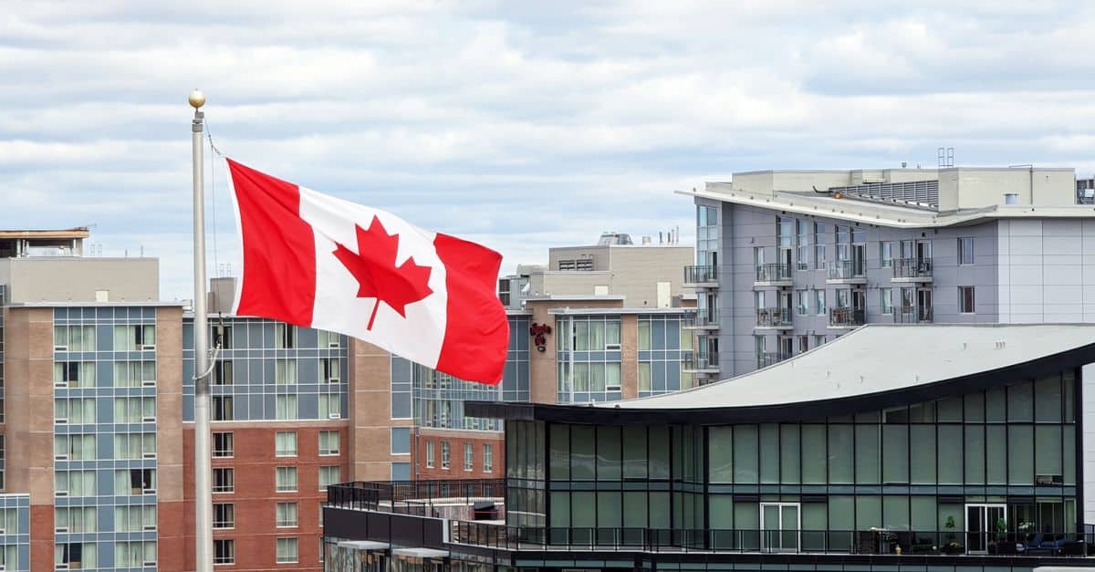Canadian flag waving over urban city buildings