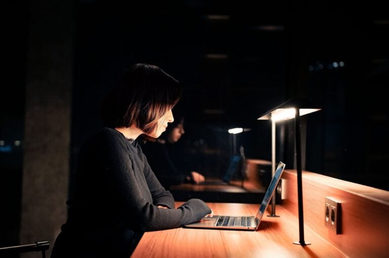 A person working late at night on a laptop in dim light, illustrating who keeps watch when a website goes down
