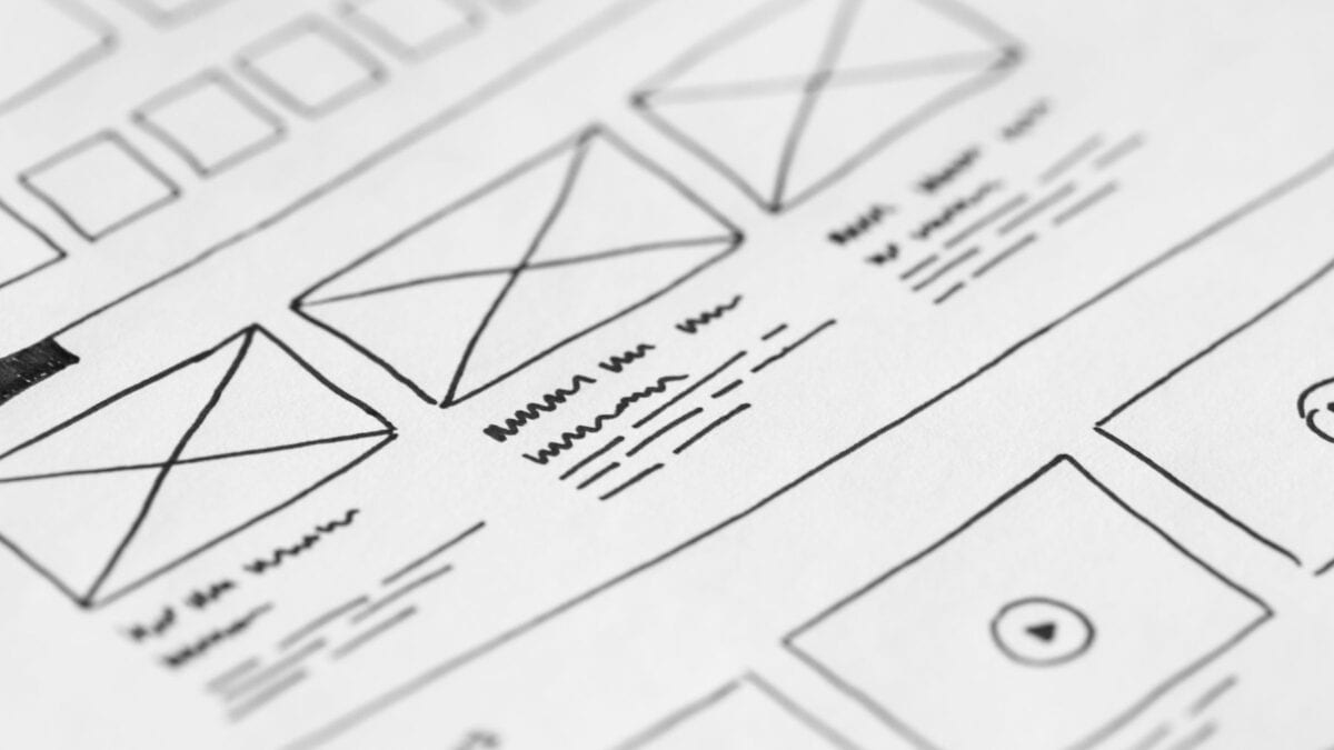 Hand-drawn website wireframe and content outline sketches on paper with a pen