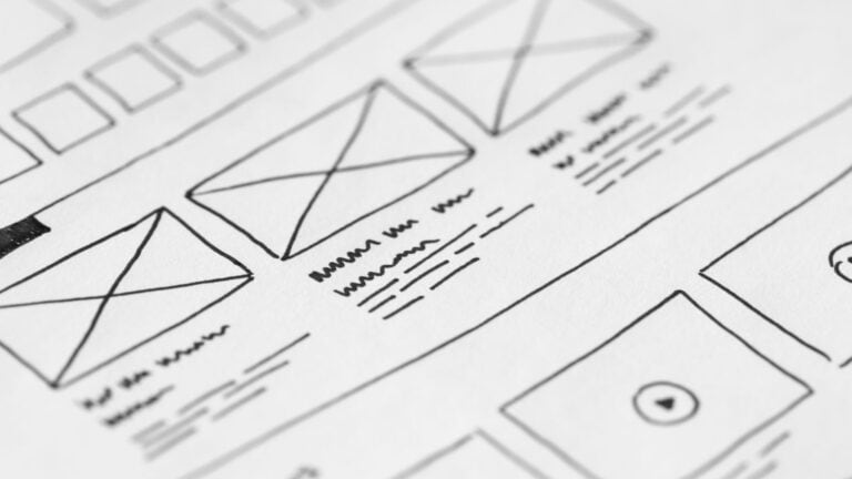 Hand-drawn website wireframe and content outline sketches on paper with a pen